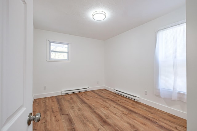 spare room featuring a baseboard radiator, wood finished floors, and baseboards