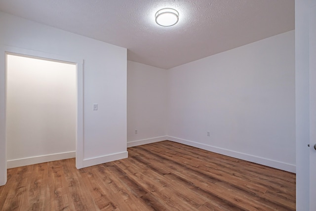 empty room with wood finished floors, baseboards, and a textured ceiling