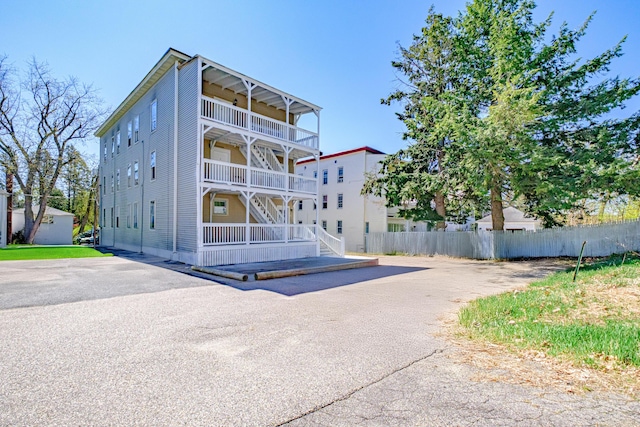 back of house with fence, a balcony, stairway, and a porch