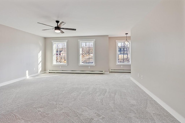 empty room featuring ceiling fan with notable chandelier, baseboard heating, a baseboard heating unit, and a healthy amount of sunlight