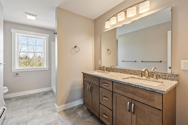 full bath featuring baseboards, toilet, double vanity, and a sink