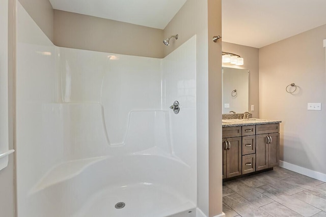 full bath with vanity, baseboards, and walk in shower