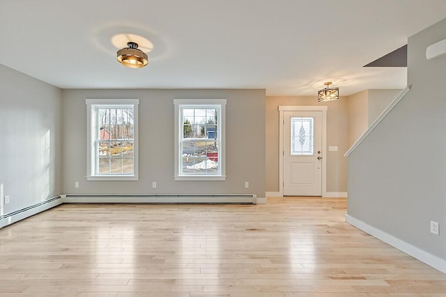 entrance foyer featuring a wealth of natural light, baseboard heating, baseboards, and light wood-type flooring