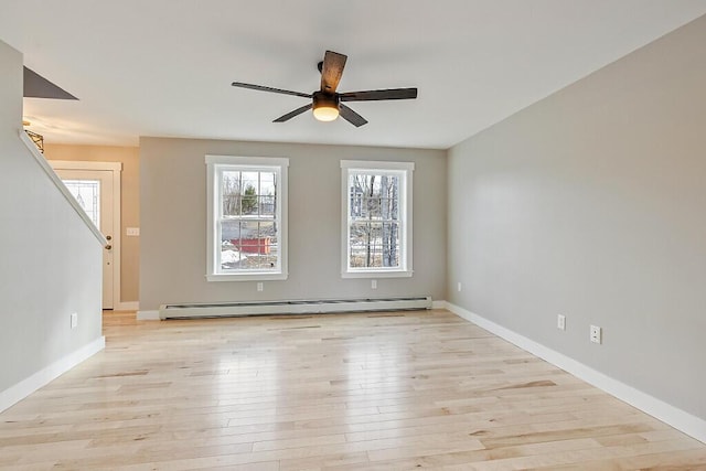 unfurnished room with stairs, light wood finished floors, a baseboard heating unit, baseboards, and ceiling fan