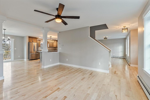 unfurnished living room featuring baseboards, a baseboard heating unit, light wood-style floors, and ceiling fan with notable chandelier