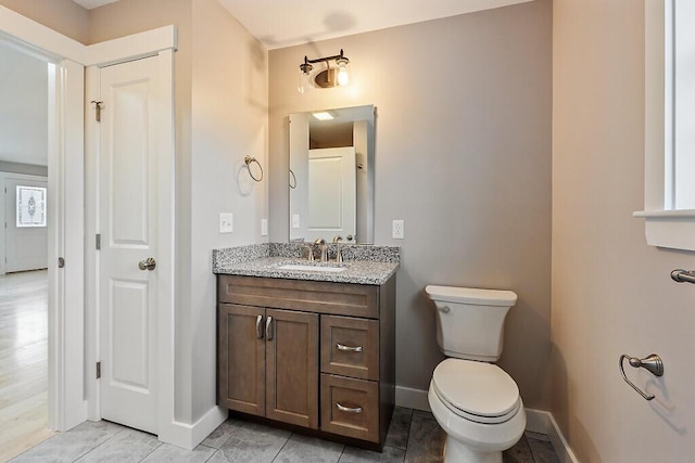 half bath featuring baseboards, toilet, and vanity