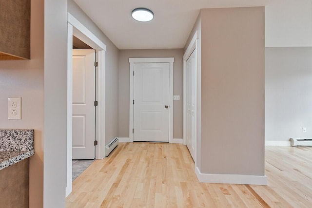 hallway featuring baseboards, light wood-style floors, and a baseboard heating unit