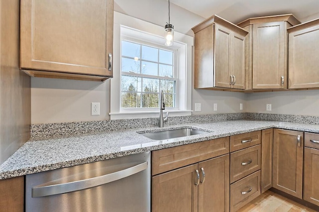 kitchen featuring dishwasher, a sink, light stone counters, and pendant lighting