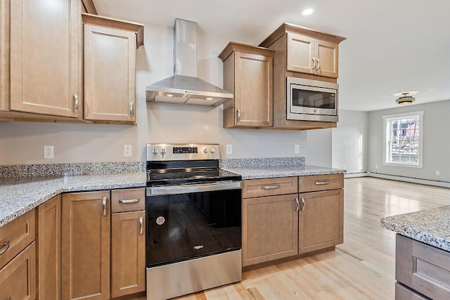 kitchen featuring stainless steel appliances, a baseboard heating unit, light wood-type flooring, light stone counters, and wall chimney range hood