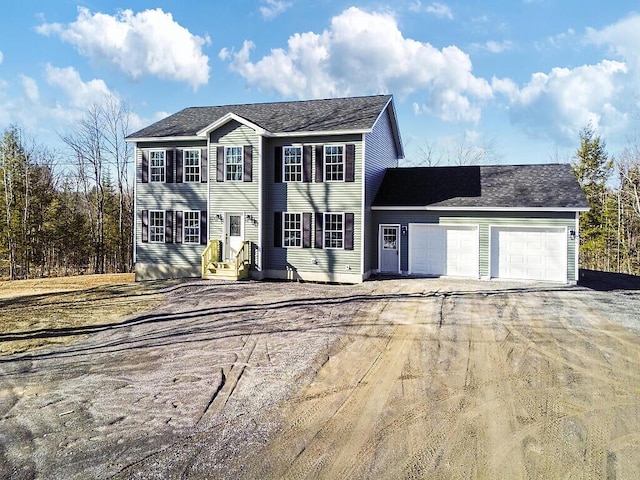 colonial inspired home featuring entry steps, driveway, and an attached garage