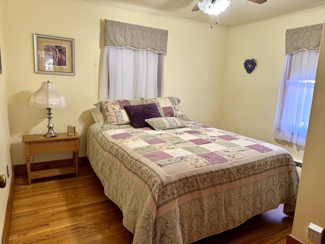 bedroom featuring wood finished floors, crown molding, baseboards, and ceiling fan