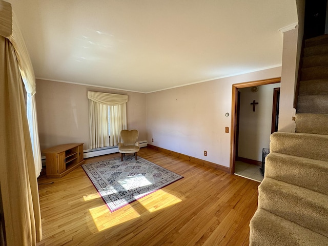 living area featuring stairway, light wood finished floors, ornamental molding, a baseboard heating unit, and baseboards