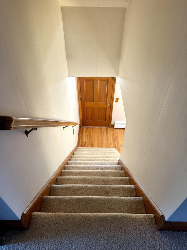stairs featuring baseboard heating and wood finished floors