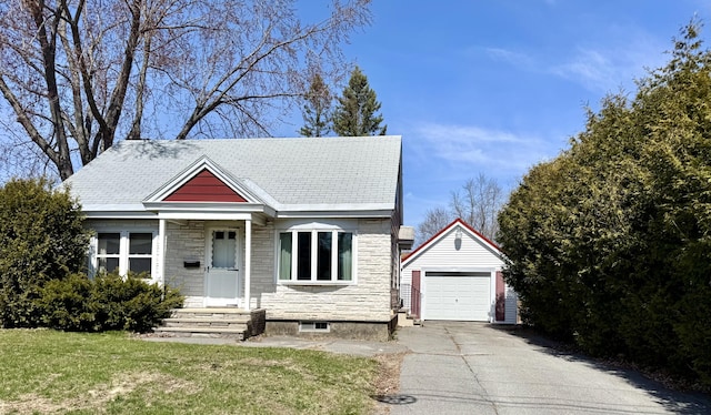 view of front of house with a detached garage, a front lawn, driveway, stone siding, and an outdoor structure