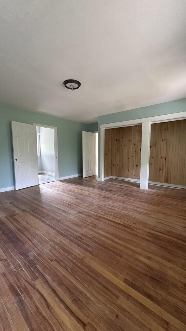 81 Maple Ridge Rd, Harrison, ME 04040 - unfurnished bedroom with dark wood-style floors, baseboards, and multiple closets