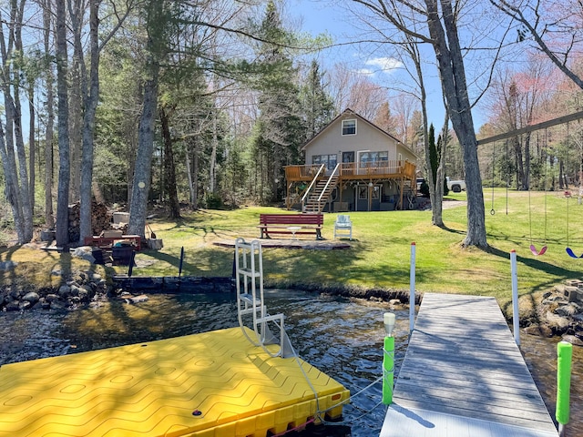 dock area with a lawn, stairs, and a deck with water view