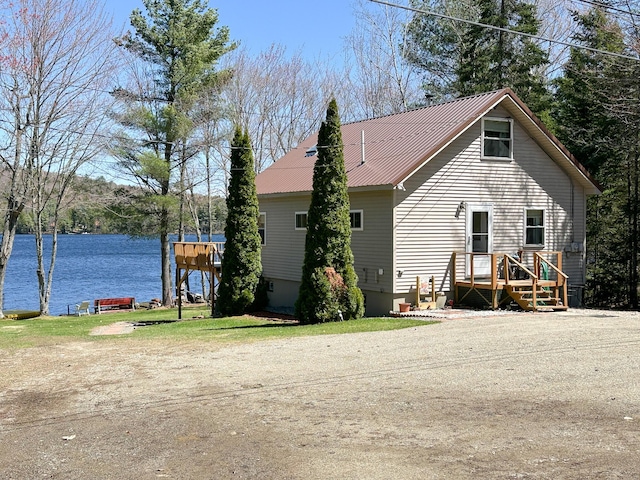 back of property with a water view and metal roof