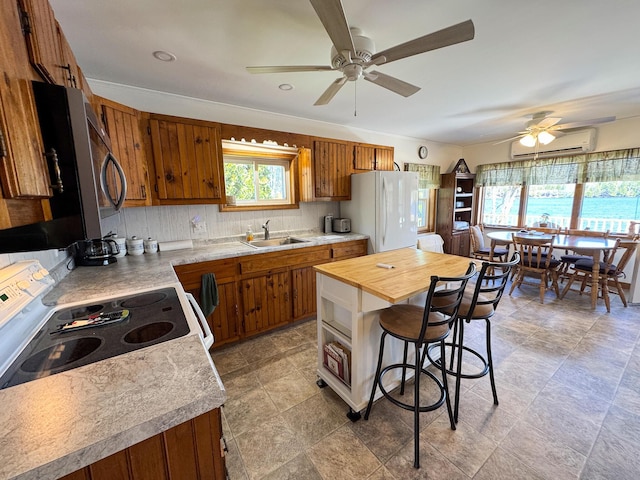 kitchen featuring freestanding refrigerator, a sink, a ceiling fan, and brown cabinets
