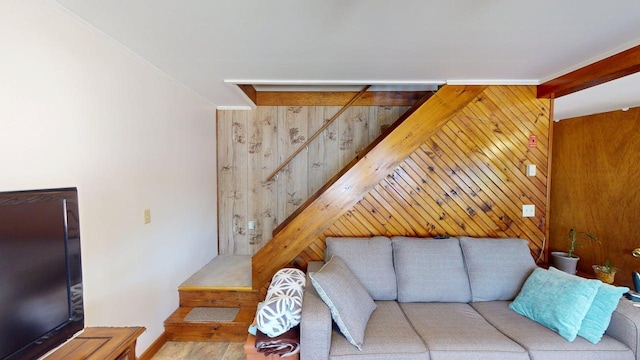 living area with crown molding, wood walls, and stairway