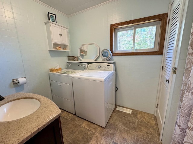 laundry room featuring independent washer and dryer, laundry area, a sink, tile walls, and ornamental molding