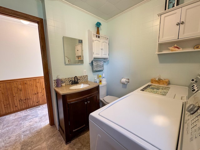 laundry area with laundry area, crown molding, visible vents, wood walls, and a sink