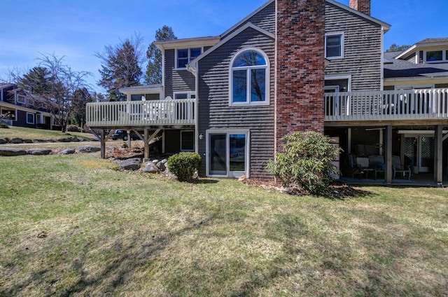 back of house featuring a deck, a chimney, and a lawn