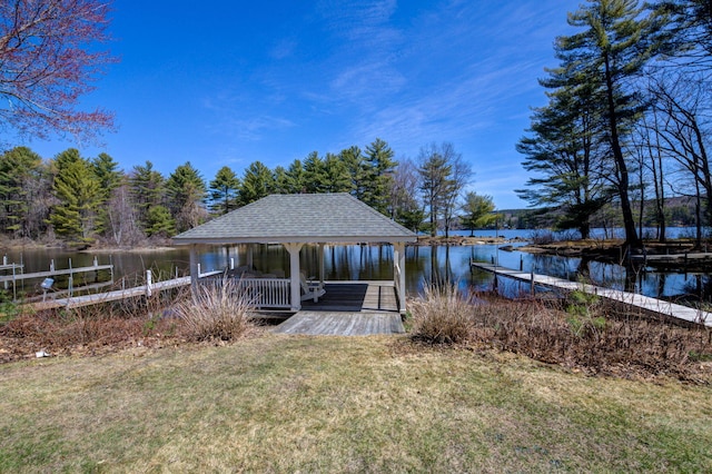 view of dock with a gazebo, a water view, and a lawn