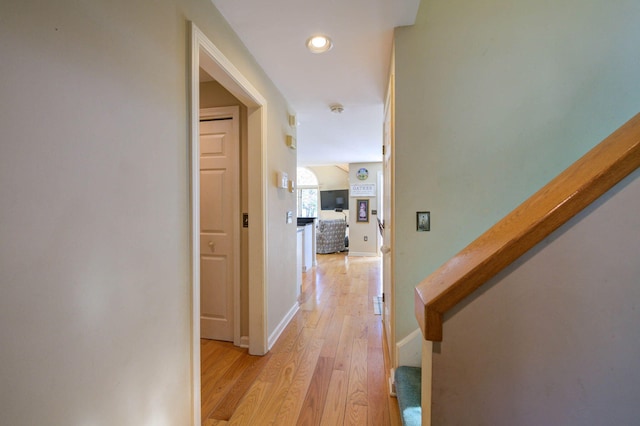 corridor with baseboards, light wood-style flooring, recessed lighting, and stairs