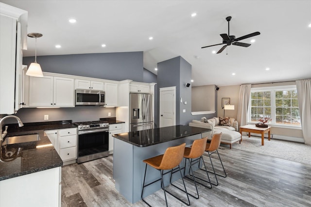 kitchen featuring a sink, a kitchen island, white cabinetry, a kitchen bar, and stainless steel appliances