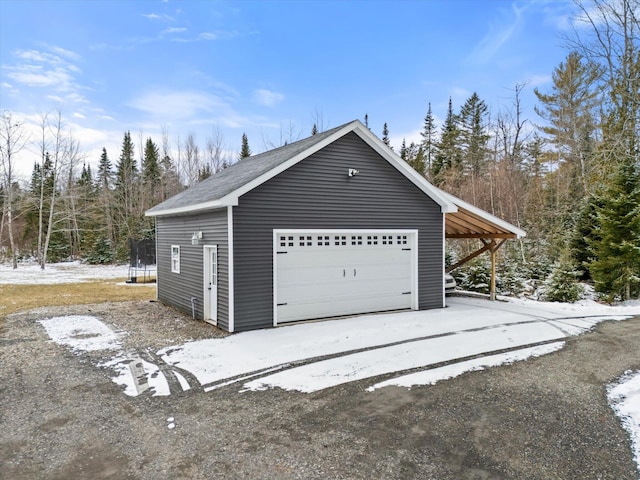 snow covered garage with a garage and a trampoline