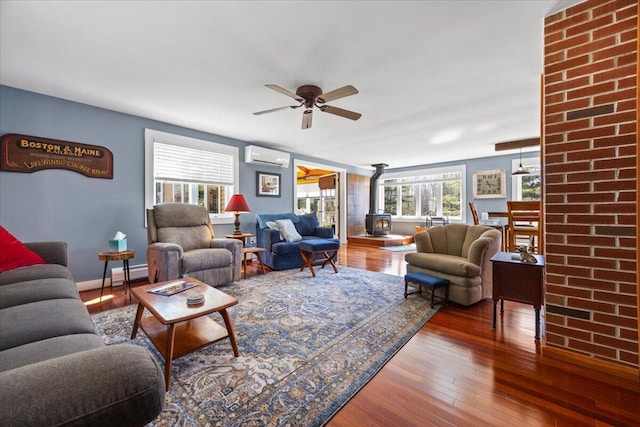 374 Youngs Ridge Rd, Acton, ME 04001 - living room with a wood stove, a wall mounted AC, hardwood / wood-style flooring, and a ceiling fan