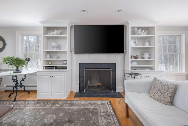 72 Natures Way, Wells, ME 04090 - living room with wood finished floors, a fireplace with flush hearth, plenty of natural light, a baseboard heating unit, and recessed lighting