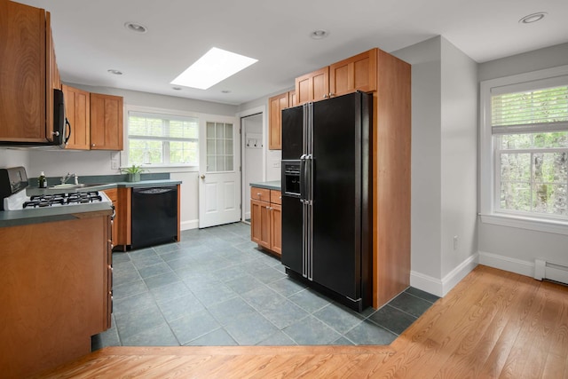 72 Natures Way, Wells, ME 04090 - kitchen featuring black appliances, a skylight, baseboards, brown cabinets, and dark countertops