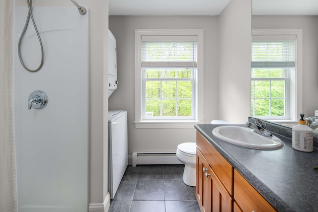 72 Natures Way, Wells, ME 04090 - bathroom featuring baseboard heating, a shower, vanity, stacked washer / drying machine, and toilet