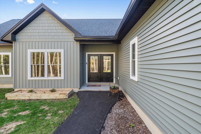 property entrance with french doors, a shingled roof, and board and batten siding