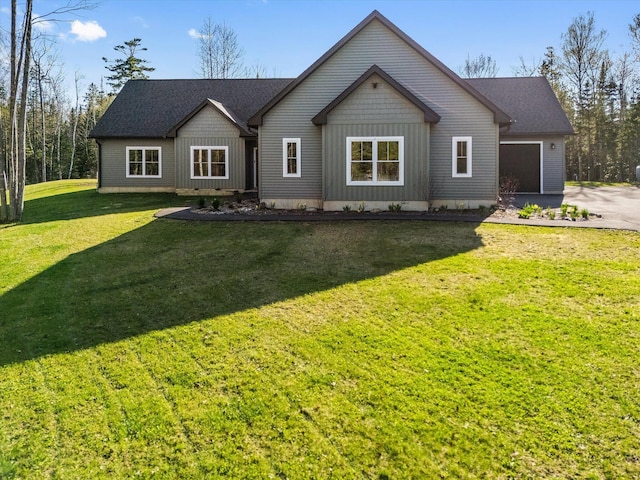 view of front of house featuring asphalt driveway, an attached garage, and a front yard