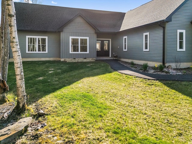 view of front of house with french doors, a front lawn, and roof with shingles