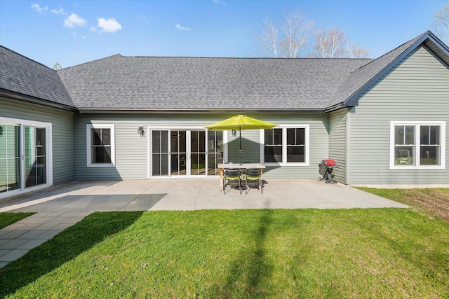 back of house featuring a patio, a lawn, and roof with shingles