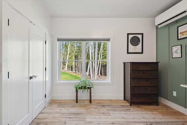 sitting room featuring a wall mounted AC, light wood-style floors, and baseboards
