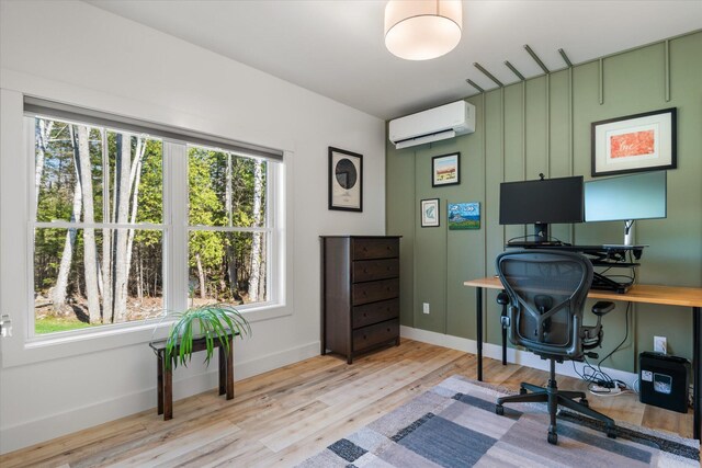 home office featuring a wall mounted air conditioner, healthy amount of natural light, wood finished floors, and baseboards