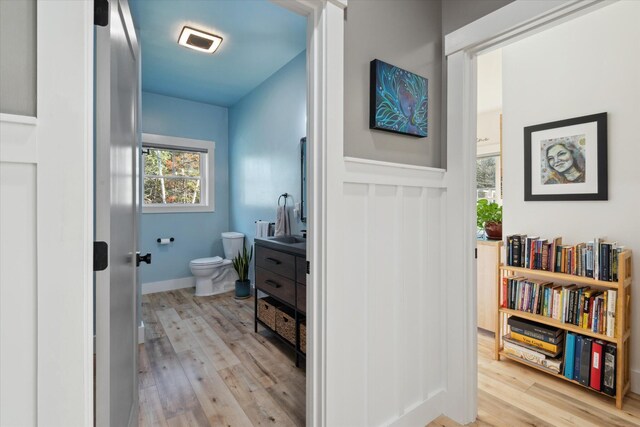 bathroom featuring toilet, wood finished floors, vanity, and a wainscoted wall