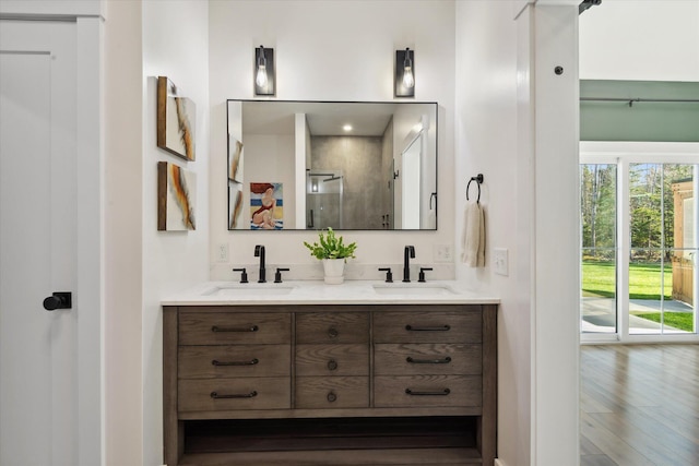 full bath featuring a stall shower, double vanity, and wood finished floors