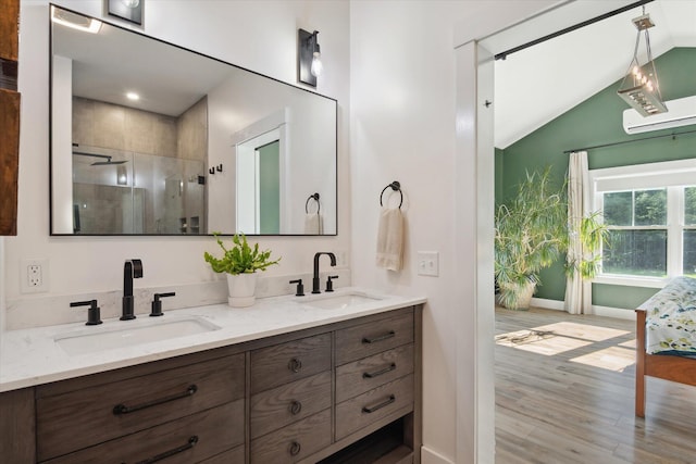 bathroom featuring vaulted ceiling, a shower stall, wood finished floors, double vanity, and baseboards