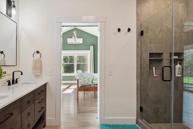 bathroom with a stall shower, double vanity, baseboards, and wood finished floors