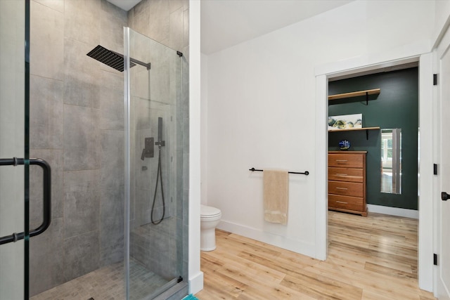 bathroom with wood finished floors, a stall shower, and baseboards