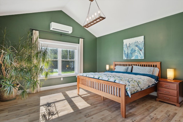 bedroom with a wall mounted air conditioner, vaulted ceiling, wood finished floors, and baseboards
