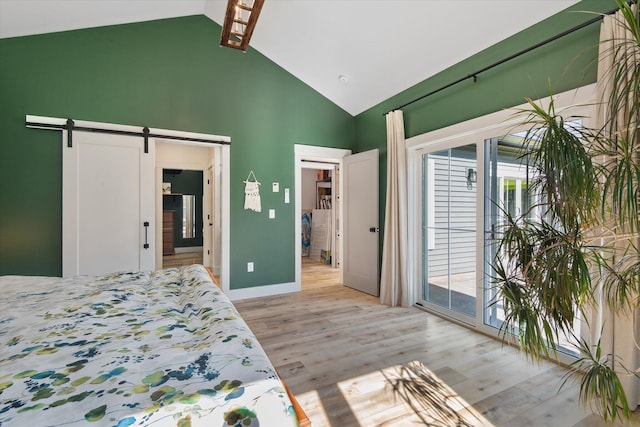 bedroom featuring a barn door, access to outside, light wood-style floors, high vaulted ceiling, and baseboards