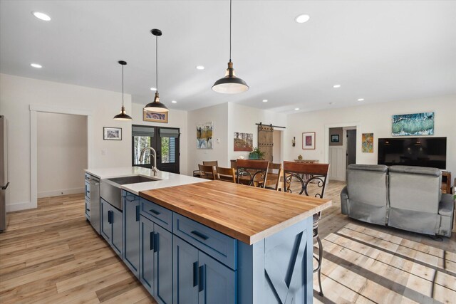 kitchen featuring light wood-style flooring, recessed lighting, a sink, wooden counters, and blue cabinets