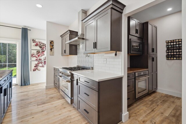 kitchen with appliances with stainless steel finishes, tasteful backsplash, light wood-type flooring, light countertops, and recessed lighting