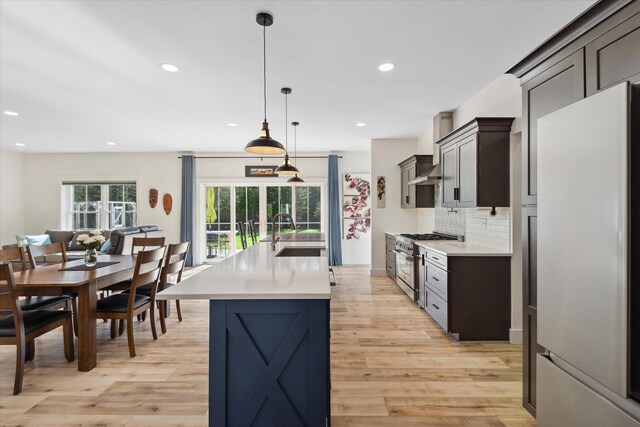 kitchen with freestanding refrigerator, stainless steel range, a sink, light countertops, and light wood-style flooring